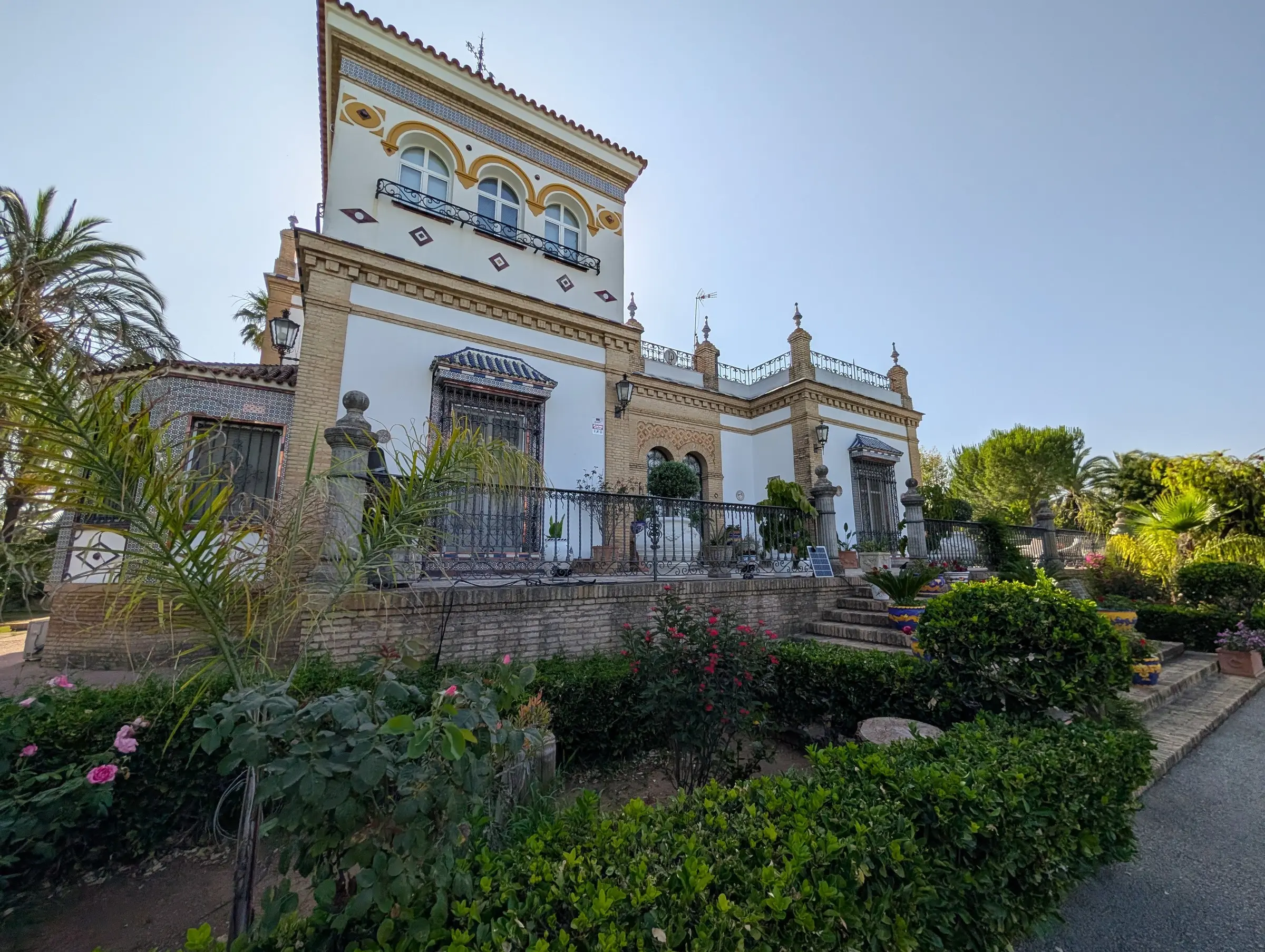 La casa principal, de estilo regionalista sevillano, con su torre, rejas y jardín delante