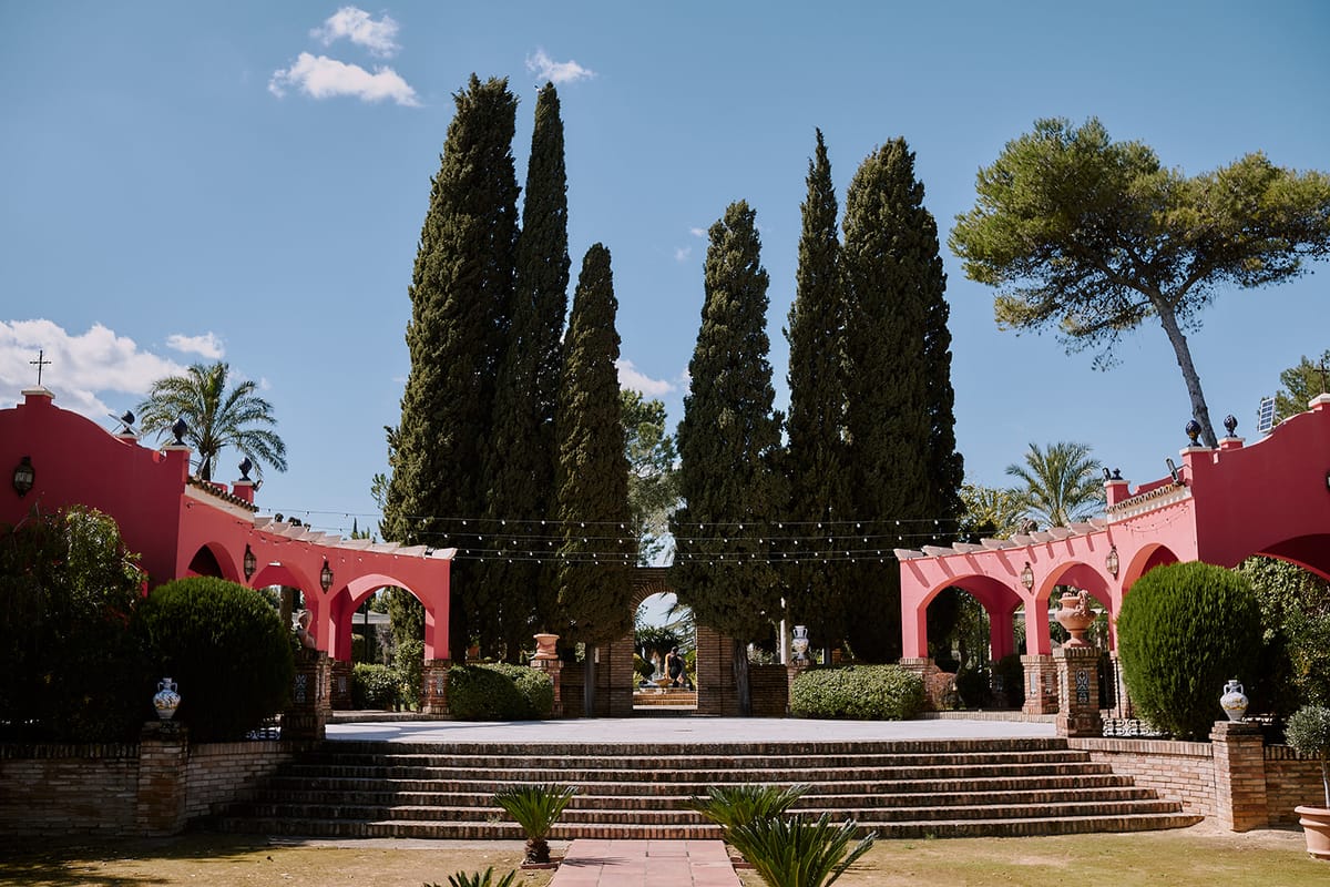 El patio de los cipreses de la Hacienda Al-Yamanah: escalinata entre dos arcadas rosas y guirnaldas de bombillas